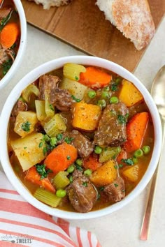 two bowls of beef stew with carrots, celery and peas