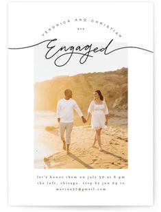 an engaged couple walking on the beach holding hands