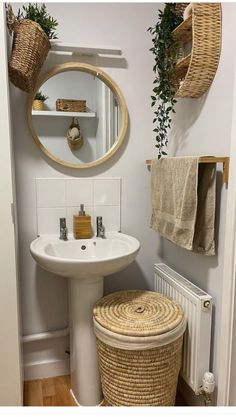 a white sink sitting under a mirror next to a bathroom vanity with baskets on the wall