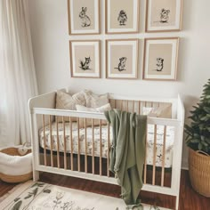 a white crib with pictures on the wall above it and a rug in front of it