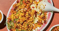 two bowls filled with food next to each other on top of a red tablecloth