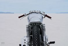 a motorcycle parked in the middle of a desert with mountains in the distance behind it