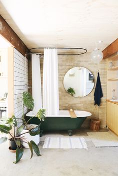 a bathroom with a bathtub, mirror and plants in the corner on the floor