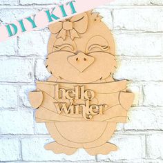 Adorn your home with the Penguin Girl Door Hanger from Janet's Craft Corner. This delightful DIY kit includes a wooden cutout of a cartoon penguin girl carrying a banner that reads hello winter. Featuring a charming bow on her head, this decorative piece is perfect for winter decor and looks lovely against a white brick wall. Penguin Door Hanger, Door Penguin, Americana Paint, Penguin Love, Winter Signs, Hello Winter, Craft Corner, Diy Craft Kits, Glue Crafts