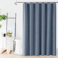 a blue shower curtain hanging on the side of a white wall next to a potted plant