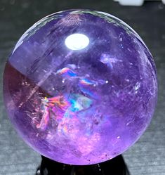 a purple crystal ball sitting on top of a black stand with a white light in it