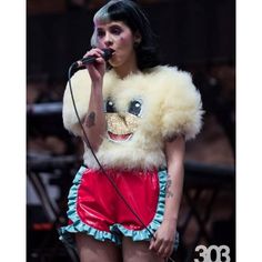 a woman in a costume singing into a microphone