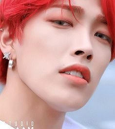 a close up of a person with red hair and piercings on their ear rings