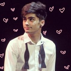 a man wearing a white shirt and black tie with hearts drawn on the wall behind him