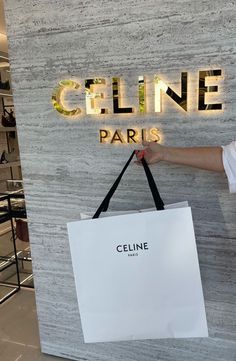 a person holding a shopping bag in front of a sign that says cline paris