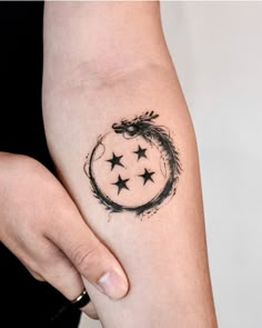 a woman's arm with stars and a dragon tattoo on the left side of her arm