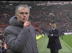 a man standing on top of a soccer field holding a finger up to his mouth