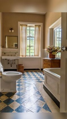 a bathroom with blue and white checkered flooring next to a bathtub, toilet and sink