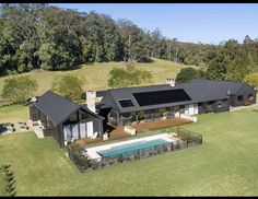 an aerial view of a house with a swimming pool in the foreground and trees on the other side