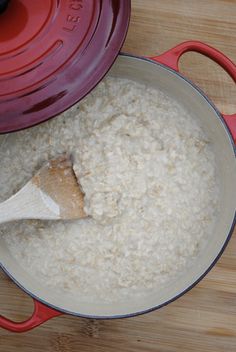 a red pot filled with oatmeal and a wooden spoon