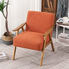 an orange chair sitting on top of a wooden floor next to a potted plant