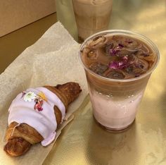 a pastry with icing on it next to a cup of coffee