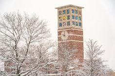 a tall clock tower with stained glass windows on it's sides in the snow