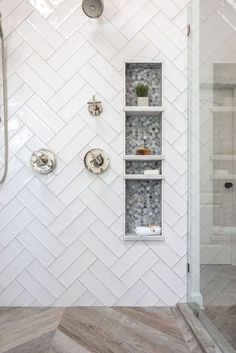 a walk in shower sitting next to a white tiled wall and wooden floored floors