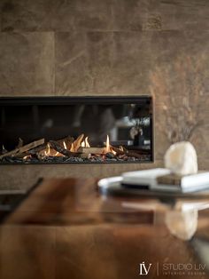 a fire place in the middle of a living room with a table and chair next to it