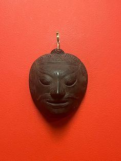 a black mask hanging on a red wall