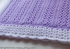 a purple and white crocheted blanket sitting on top of a table