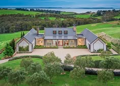 an aerial view of a house in the middle of a lush green field with trees and bushes