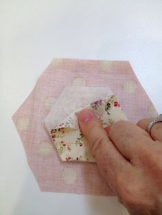 a hand is holding fabric on top of a piece of cloth