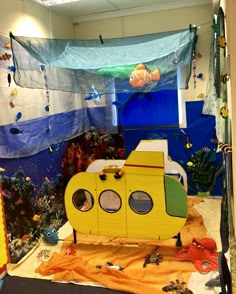 a yellow submarine boat sitting on top of a floor next to a wall covered in fish