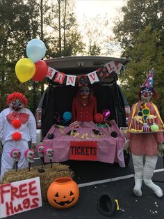 two clowns are standing in the back of a truck with balloons and decorations on it