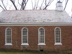 an old brick building with three windows and a clock tower on the top of it