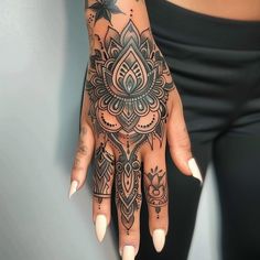 a woman's hand with an intricate tattoo design on her left arm and wrist