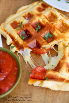 a waffle topped with bacon and cheese next to a bowl of ketchup