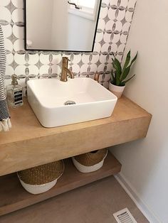 a bathroom sink sitting under a mirror on top of a wooden counter next to a potted plant