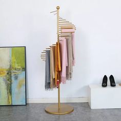 a rack with scarves and shoes on it in front of a wall mounted painting