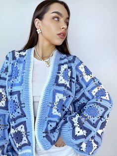 a woman wearing a blue and white crocheted cardigan