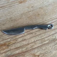 a knife that is sitting on top of a wooden table next to a piece of metal