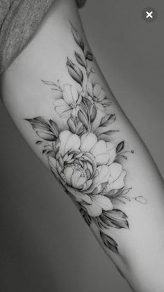 a woman's arm with flowers on it and leaves in the middle of her arm