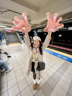 a woman is holding her hands up in the air while standing on a tiled floor