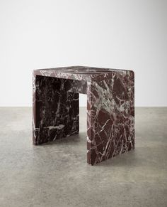 a marbled side table sitting on top of a cement floor