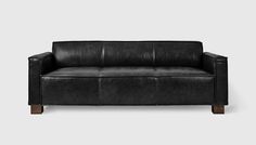 a black leather couch sitting on top of a white floor