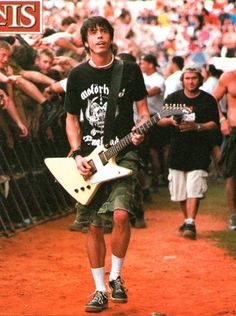 a man with a guitar walking in front of a crowd