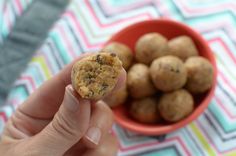 a hand holding a cookie in front of a bowl of cookies