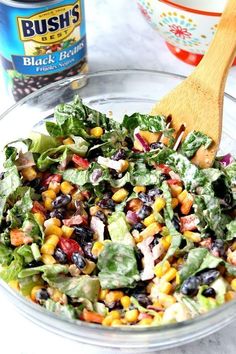 a salad with black beans, corn and lettuce is in a glass bowl