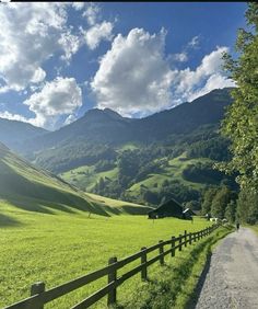 a dirt road going through a lush green valley