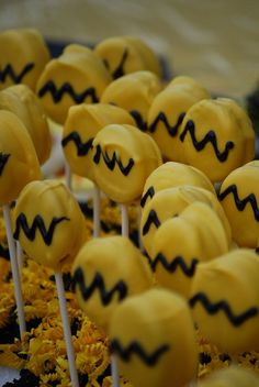 yellow cake pops with black icing and smiley face faces on them are arranged in a row