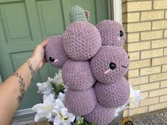 a person holding a bunch of crocheted stuffed animals in front of a door