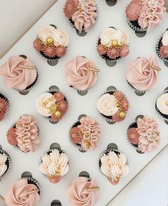 cupcakes with pink frosting and gold decorations are arranged on a white surface