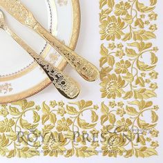 two golden forks and spoons on a white plate next to gold lace doily