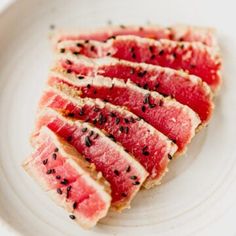 slices of tuna with black pepper on top sit in a white bowl, ready to be eaten